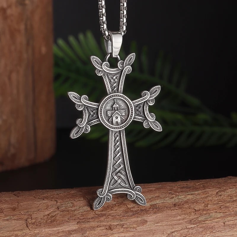 Pendentif orthodoxe khachkar arménien en acier, ambiance spirituelle avec fond sombre et feuillage