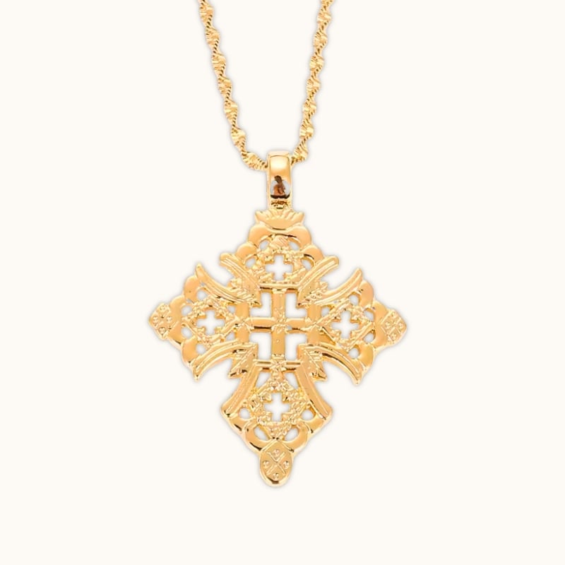 Pendentif croix éthiopienne finition or avec design rond et ajouré, sur fond clair