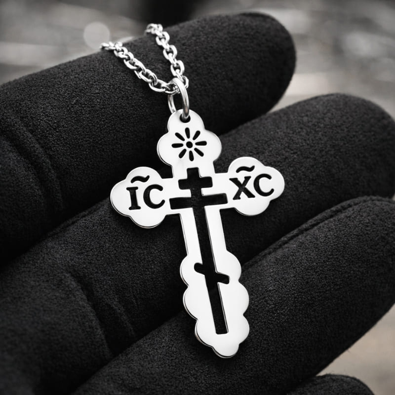 Collier croix orthodoxe russe en argent dans la main d'un bijoutier