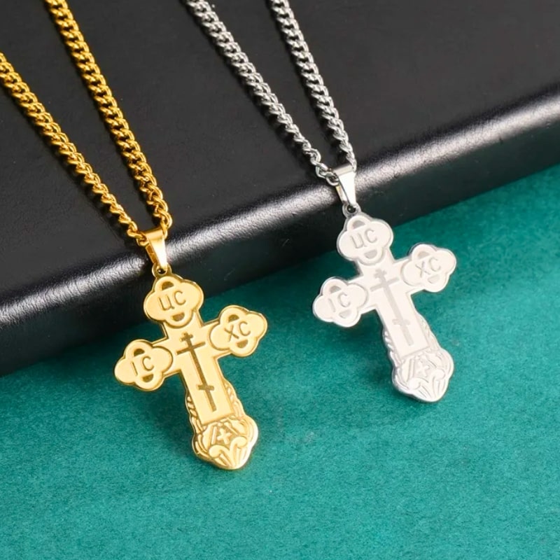 Pendentifs croix orthodoxes serbes en argent et en or posés sur fond vert – bijoux religieux pour homme et femme