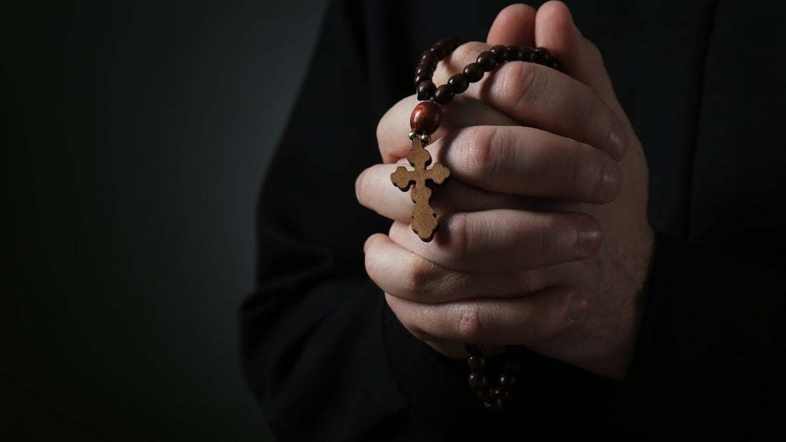 Mains jointes tenant un chapelet orthodoxe en bois avec une croix.
