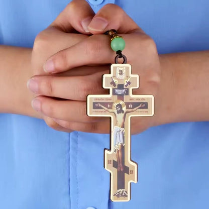 Collier croix orthodoxe en bois porté dans les mains en prière