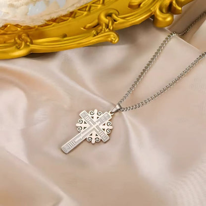 Pendentif croix serbe en argent posé sur un tissu beige