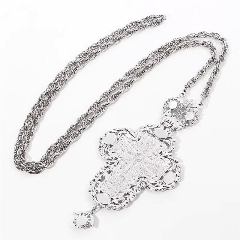 Collier avec pendentif croix argentée ornée de pierres turquoise et d'une longue chaîne.