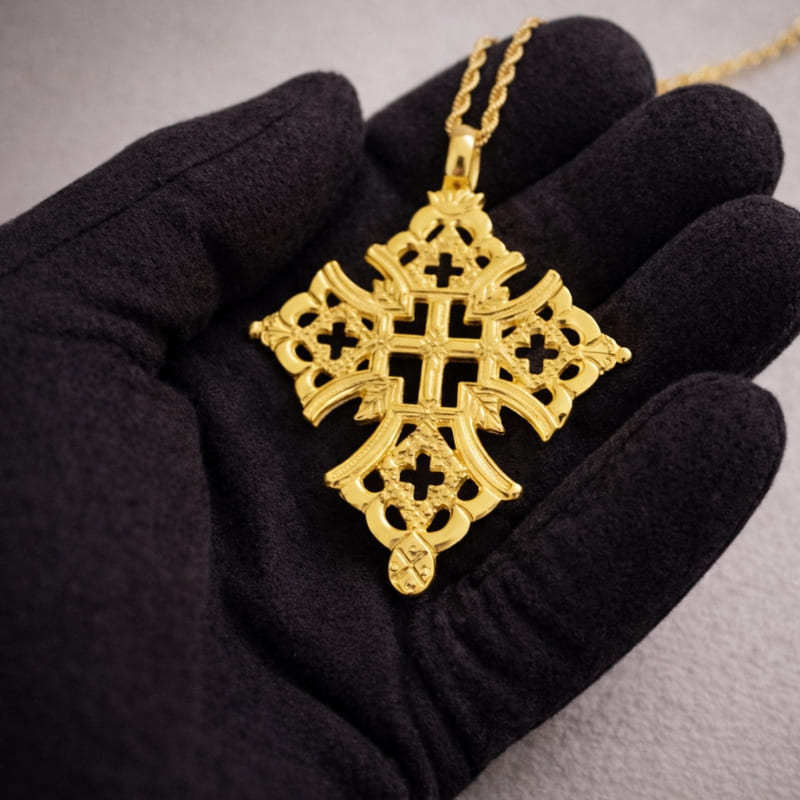 Collier croix éthiopienne copte en or dans la main d'un bijoutier