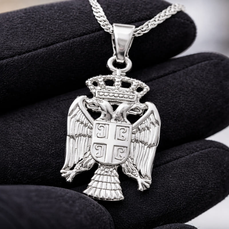 Pendentif aigle bicéphale serbe en argent dans la main d'un bijoutier