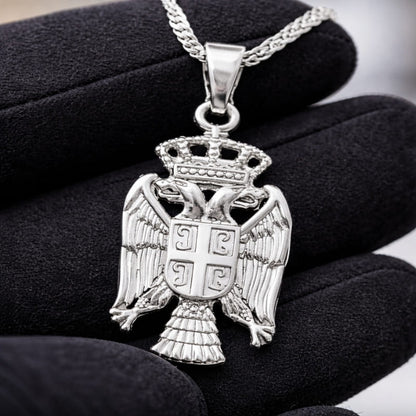 Pendentif aigle bicéphale serbe en argent dans la main d'un bijoutier