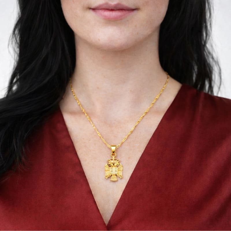 Pendentif aigle de Serbie en couleur or porté par une femme 