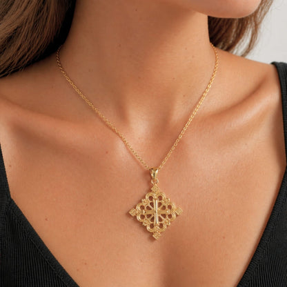 Collier en croix éthiopienne dorée portée par une femme dans un studio photo