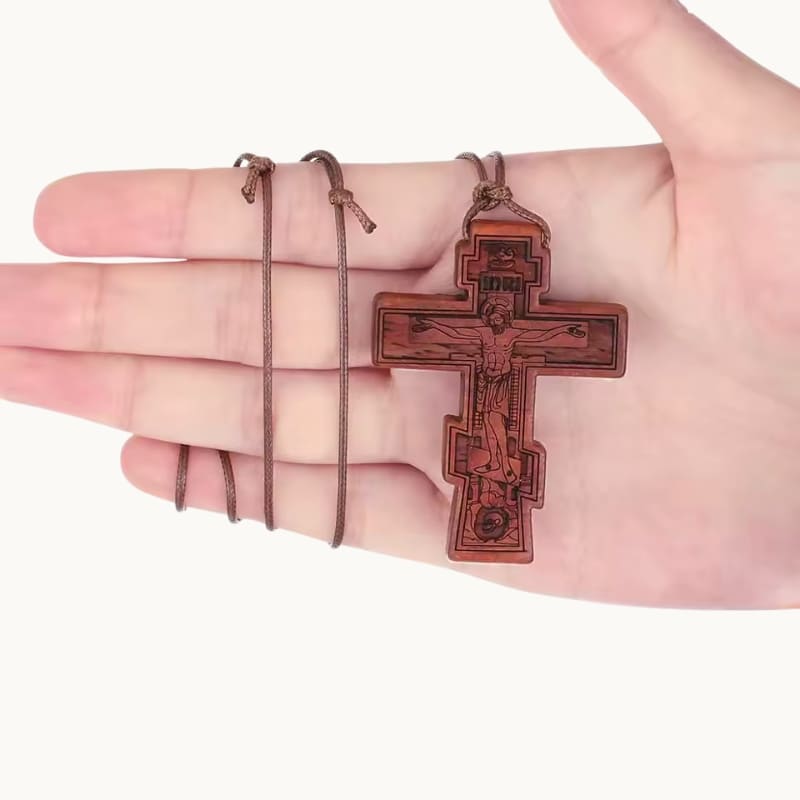 Collier croix orthodoxe en bois tenu dans une main